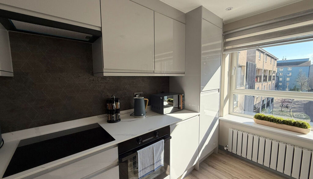 Contemporary open-plan kitchen installation in Edinburgh with marble worktops, dining area, and minimalist design by AVO Renovations.
