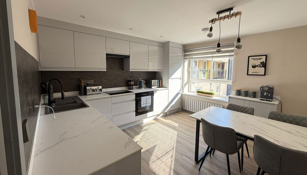 Modern grey kitchen installation in Edinburgh with integrated oven, sleek cabinets, and sunlight through window – AVO Renovations.
